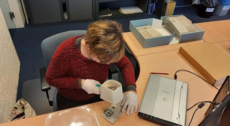 Een Collectievrijwilliger van Oorlogsmuseum Overloon probeert slecht leesbare, handgeschreven gegevens op een Persoonsbewijs te ontcijferen. (Foto: Oorlogsmuseum Overloon)